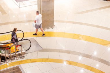 Sabahları alışverişi olan bir adam boş bir alışveriş merkezinden geçiyor. Yukarıdan görüntüle