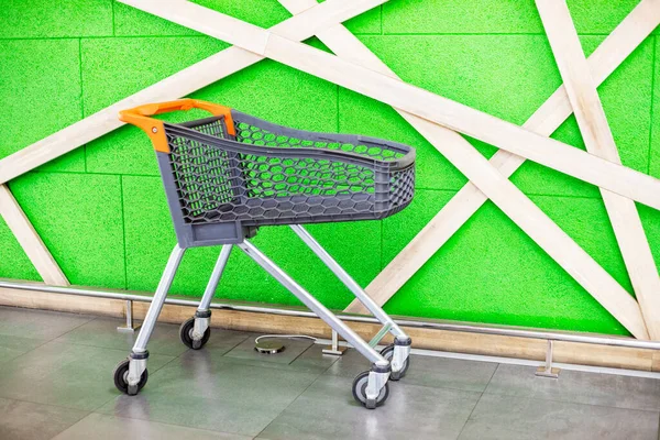 Zakupy Pusty Wózek Plastikowy Tle Zielonej Ściany Centrum Handlowym Zakupy — Zdjęcie stockowe