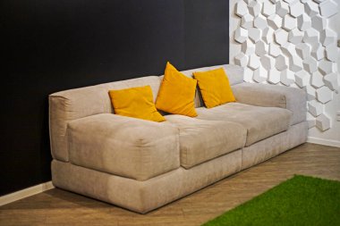 Modern bir iç mekanda sarı yastıklı yumuşak bir kanepe. Ofiste dinlenebileceğim bir yer.