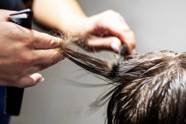 Koyu sarı saçlı bir çocuğun tarağının altında makasla kesilmiş. Moda saç kesimi