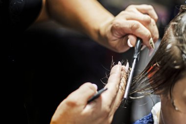 Kadın barbekücü ıslak saçların taraklı kısmının altını kesiyor. Saç kesimi ana sınıfı.