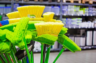 Dükkandaki temizlik için sarı ve yeşil süpürgeler.