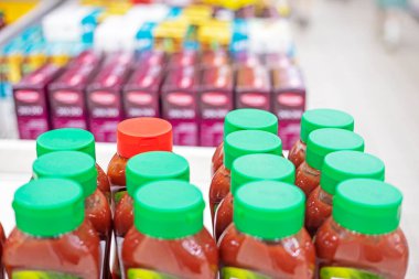 Bir süpermarkette plastik kapaklara sarılı soslar ve baharatlar.