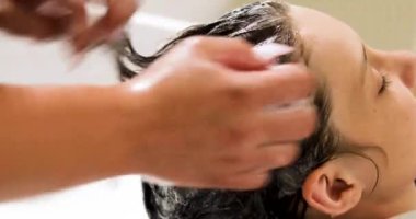 Barbekücü, saç kesiminden önce genç bir çocuğun kafasını yıkar. Saç bakımı ve bakımı