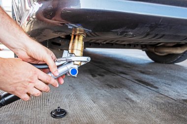 Erkeklerin elleri LPG makinelerini doldurmak için gaz tabancası tutuyor. Ekonomi ve Dünya Krizi