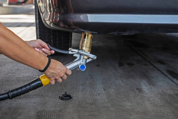 woman\'s hand holds a gas gun after refueling an LPG car. The Economy and the World Crisis