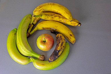 Yeşil bir elmanın etrafında muz demetleri