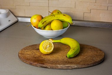 Tahta kesme tahtasının üzerinde yarım limonlu muz ve bıçak.