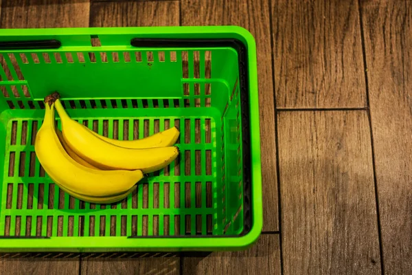 putting bananas in the green grocery basket in the supermarket