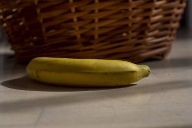 Sarı muz, rattan bir sepetin yanında.