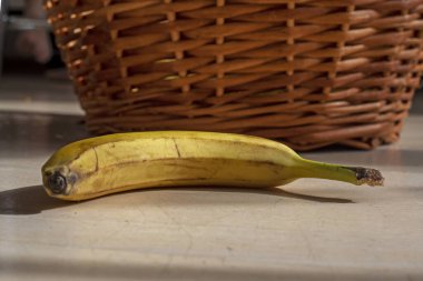 Sarı muz, rattan bir sepetin yanında.