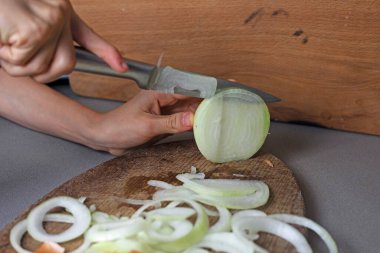 Kız, çiğ soğanı bıçakla sebze salatası için halkalara ayırıyor.