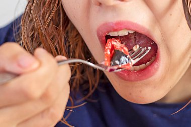 Tenager ağzı açık bir çatalla sebze salatası yiyor.