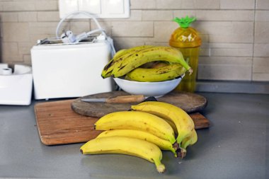 Mutfaktaki tezgahın üstünde olgun sarı muzlar var.