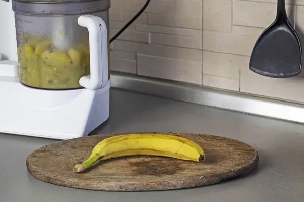 mashing bananas and apples in a food processor in the kitchen