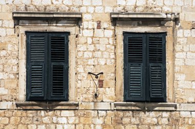 Duvarda kepenkleri kapalı antika pencereler ve şövalye masonluğu.