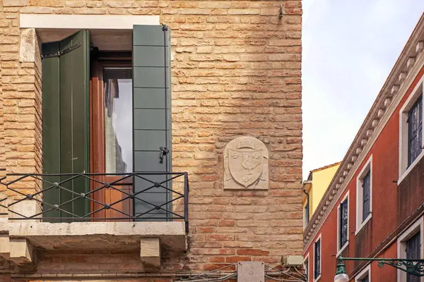 Venetian balcony window with green shutters on an ancient brick building