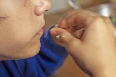 Bir çatalla sebze salatası yiyor, ağzı açık.