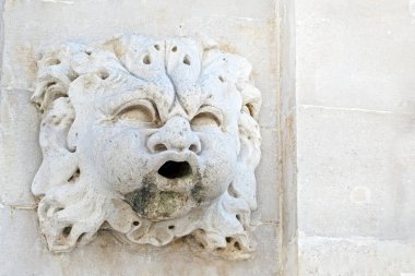 Mermer bir çeşme elementi ve ortasında bir kafa.