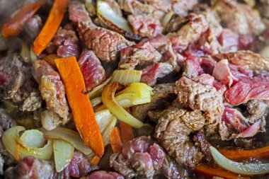 Kızartma tavasında kesilmiş çiğ et pişir. Sebzelerle, üst manzara.