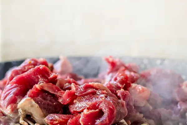 cook raw fresh meat cut into pieces in a frying pan. Cooking at home in the kitchen