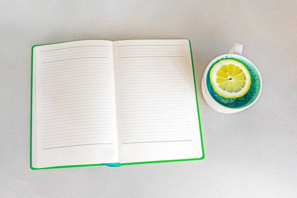 open weekly planner on the table next to a cup of lemon. Good morning, breading of the day, week, month, year
