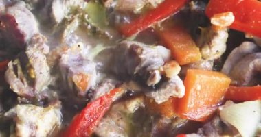 Kızartma tavasında kabaklı, havuçlu ve soğanlı haşlanmış et parçaları.