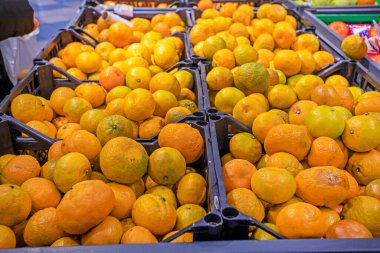 Bir süpermarkette kaplarda mandalina ve portakallar. Bütçe tasarrufu