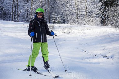 Mutlu dağcı çocuk karlı bir ormanda bir dağda duruyor.