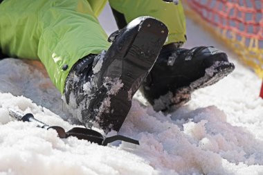 Kayakçı karlı bir yamaçta kayak botları giyer. Aileyle aktif tatil