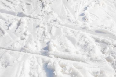 Güneşli bir günde kayakçı izleri taşıyan beyaz karın soyut arkaplanı