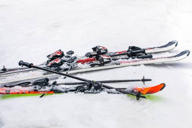 Güneşli bir günde karlı bir yamaçta kayak direkleri ve kayaklar