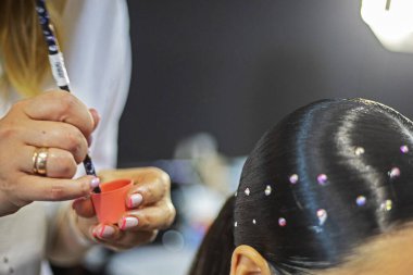 Bir balo salonu spor turnuvası için saçlarını küçük taşlarla süsleyen stilist, Olimpiyat dışı spor