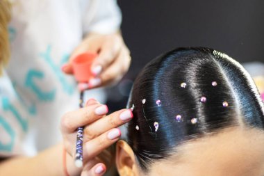 Bir balo salonu spor turnuvası için saçlarını küçük taşlarla süsleyen stilist, Olimpiyat dışı spor