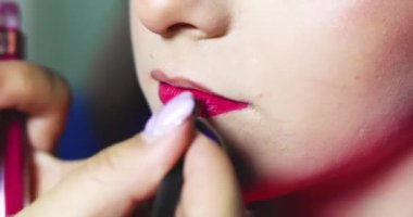 Stilist kızın dudaklarını fırçayla kızıla boyuyor. şık makyaj