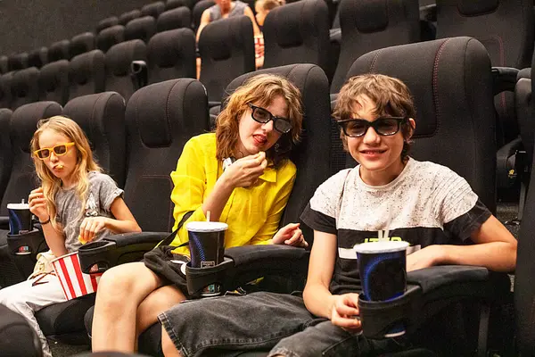 stock image children sit in the cinema hall with popcorn before watching. family weekend