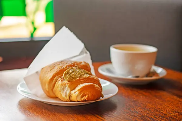 stock image hot croissant with pistachio cream and a cup of tea. snack. Back to school