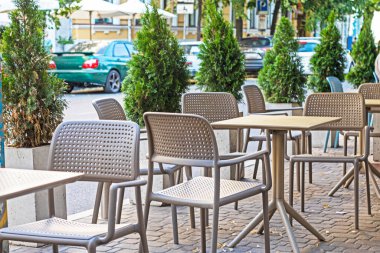 Yol boyunca hasır mobilyaları ve yeşil haydutları olan bir sokak kafesi.