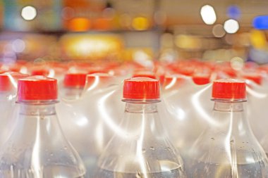 drinks packaged in plastic containers with red caps and wrapped in thick film in a supermarket clipart