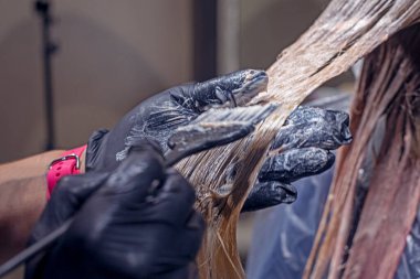 Siyah eldivenli stilist saçlarını boyuyor. Parlak pembe ve mor. Bir güzellik salonunda mutlu bir kızın üzerinde.