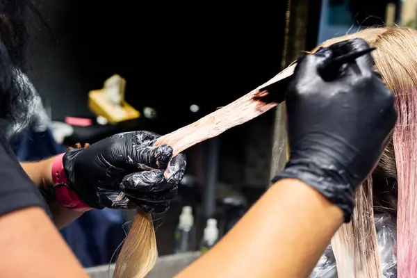 stock image stylist dyes strands of hair bright pink and purple on a happy girl in a beauty salon