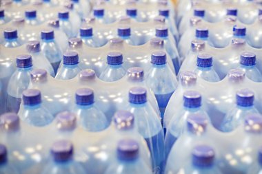 Süpermarketteki raflarda plastik kaplarda paketlenmiş içme suyu.