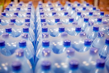Süpermarketteki raflarda plastik kaplarda paketlenmiş içme suyu.