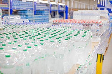 Süpermarketteki raflarda kapaklı plastik kaplarda paketlenmiş içme suyu.