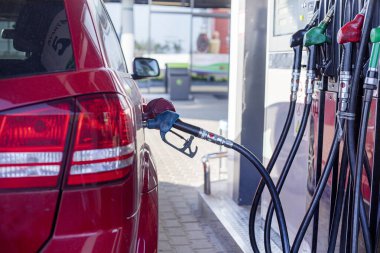 Benzin istasyonundaki kırmızı araba benzinle doluyor. Ekonomik kriz. Petrol ve akaryakıt fiyatlarında artış