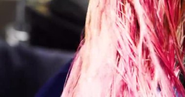 Parlak pembe ve mor saç tellerini boyamadan sonra saç kurutma makinesiyle kurutmak. şık saç stilleri.