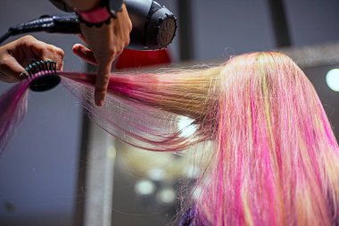 Kuaför, boyamadan sonra parlak pembe ve mor saç tellerini kurutuyor. şık saç stilleri