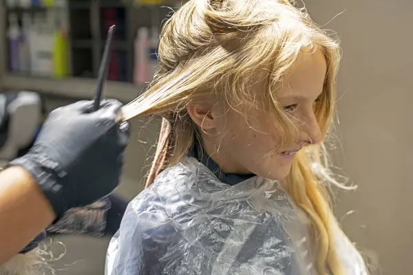 Stock image hairdresser stylist dyes beautiful blonde hair of a girl in bright pink strands. Modern hairstyles