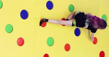 Koşumlu bir kız zaman için bir ip ile eğitim duvarına tırmanıyor. Çocuklar için antrenman ve spor. Okula geri dön.