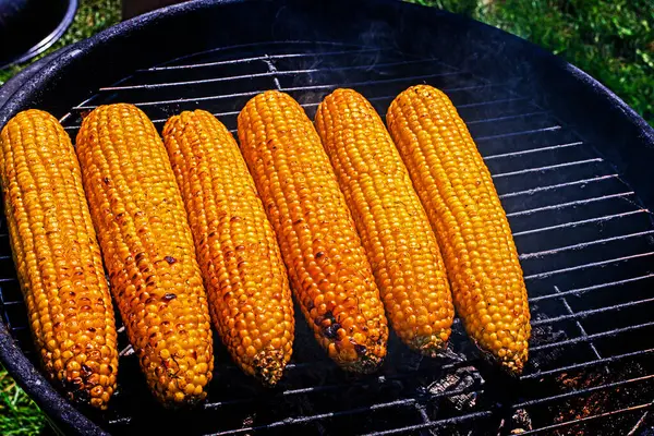 stock image cooking sweet corn on the grill on a barbecue on a sunny day. Healthy vegan food